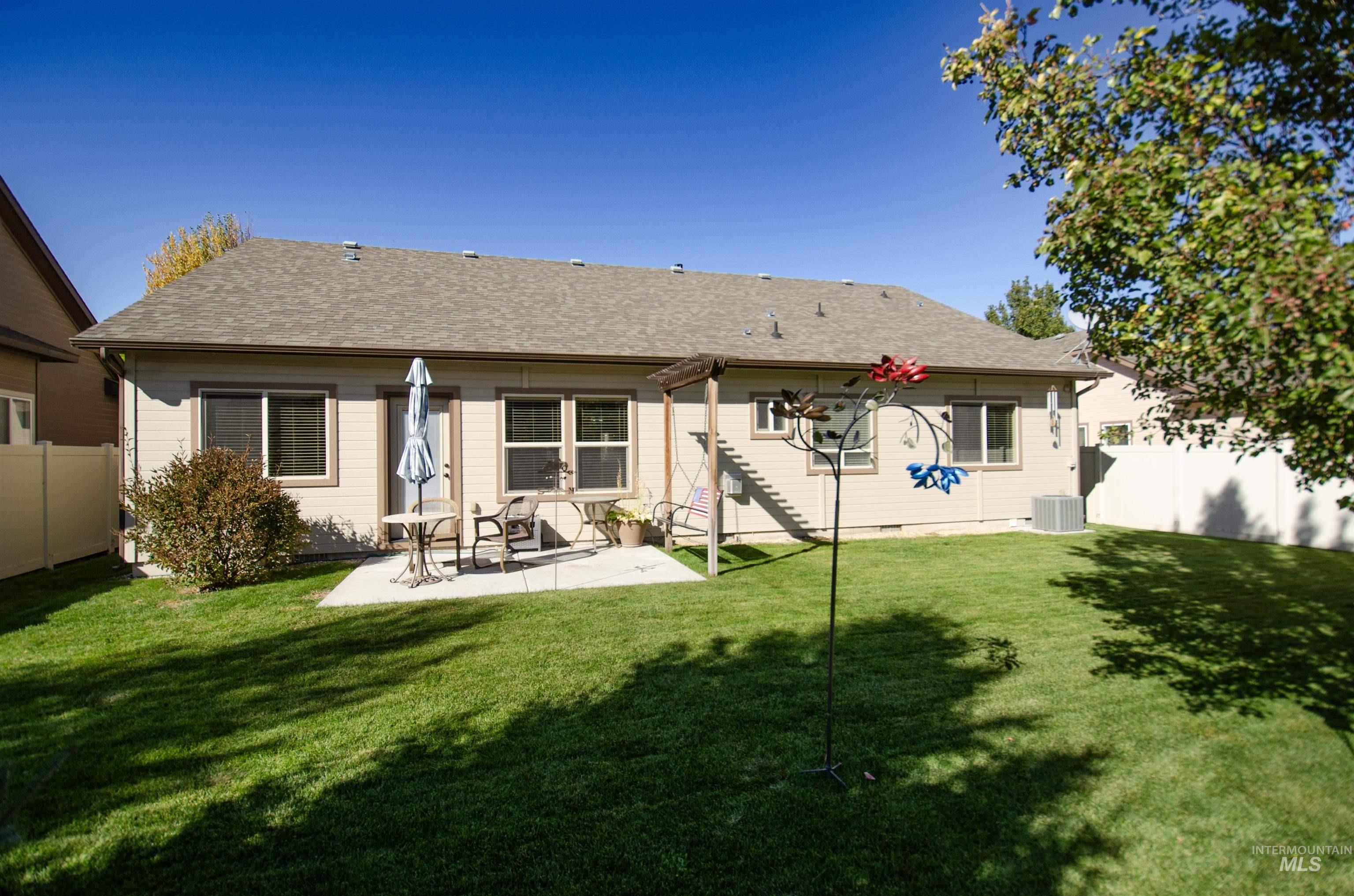 Rear view of house with a fenced backyard, a shingled roof, and a patio