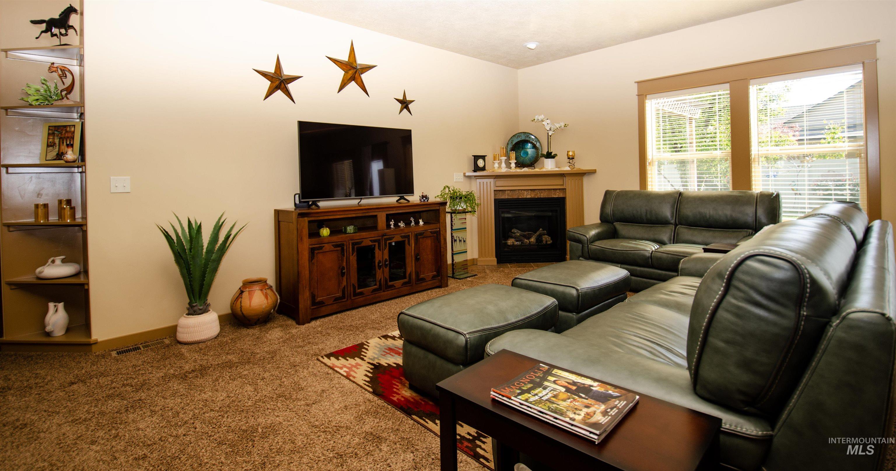 Living room with a glass covered fireplace and carpet floors