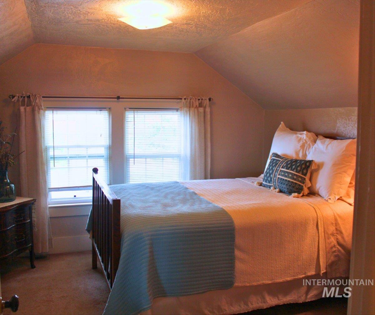 Bedroom featuring vaulted ceiling, a textured ceiling, and carpet