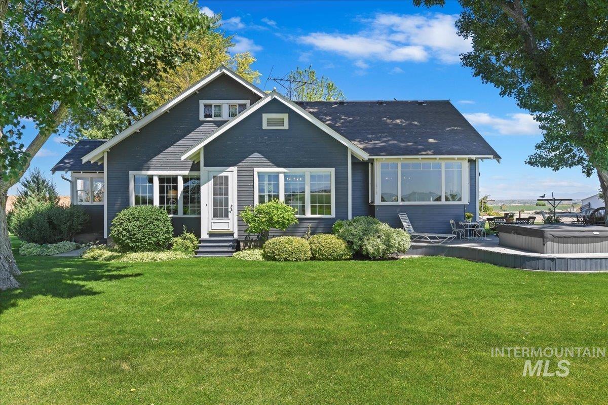 Side view of property featuring a lawn, entry steps, an outdoor hot tub, and a patio area
