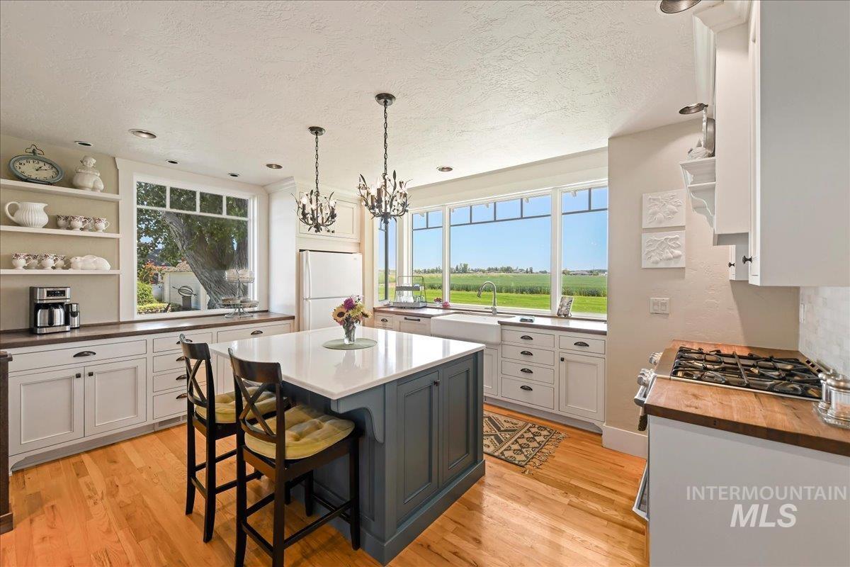 Kitchen featuring open shelves, freestanding refrigerator, a kitchen breakfast bar, pendant lighting, and light wood finished floors
