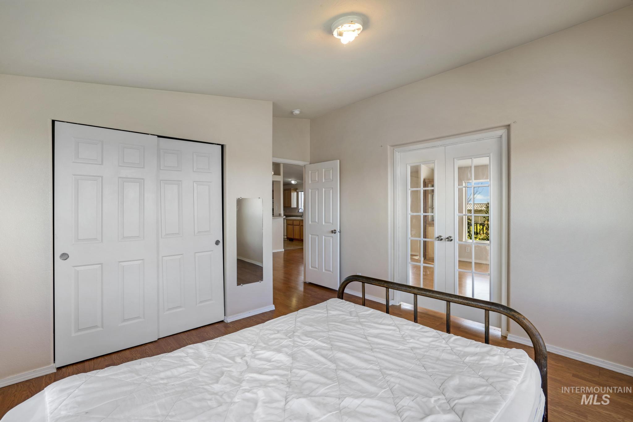 Bedroom featuring french doors, dark wood-style floors, and a closet