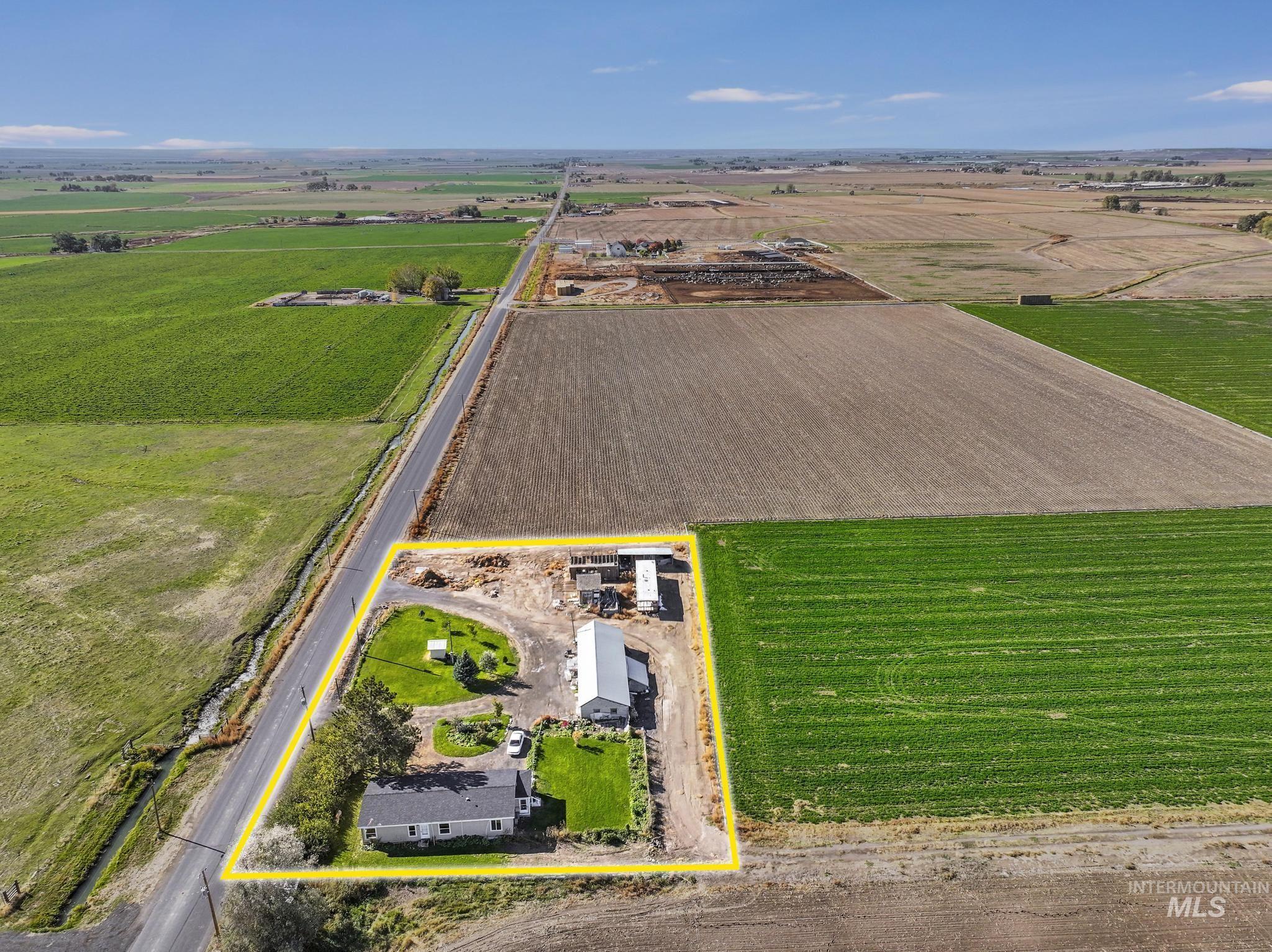 Aerial view of sparsely populated area featuring property parcel outlined and rows of crops