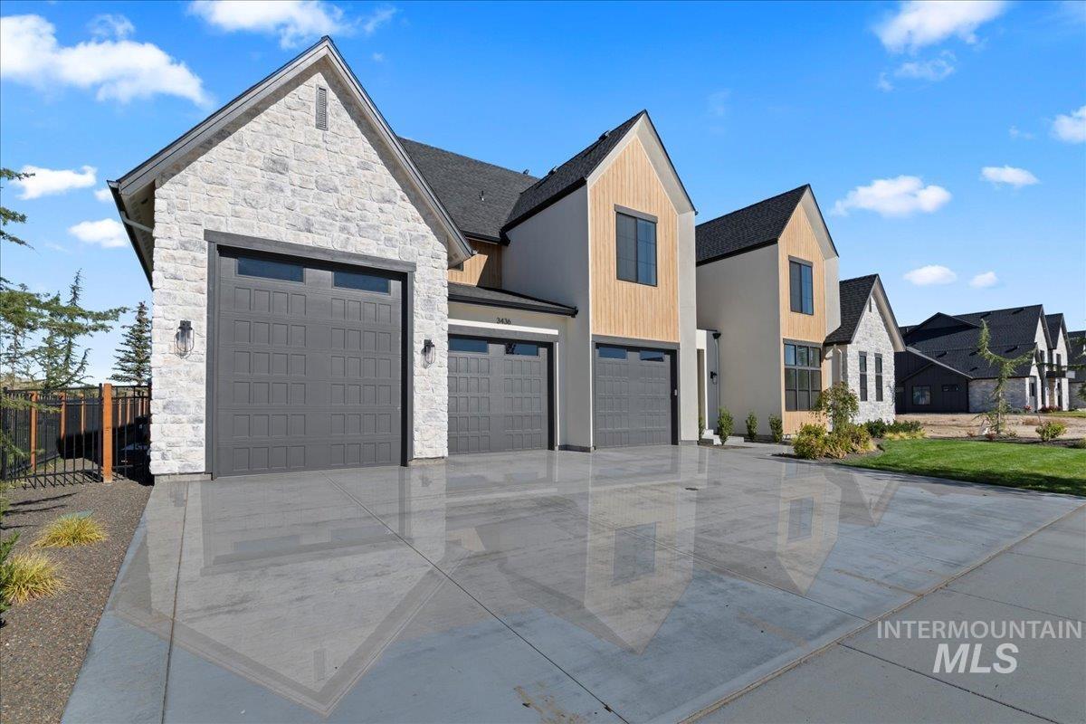 View of front facade with stone siding, driveway, and a residential view