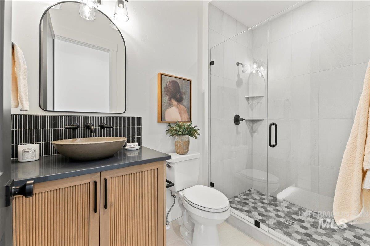 Full bath featuring vanity, a stall shower, backsplash, and tile patterned flooring