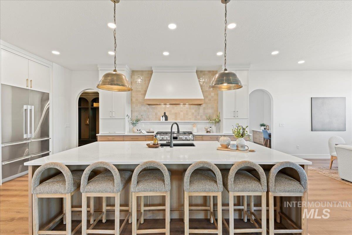 Kitchen featuring arched walkways, light wood-style flooring, high quality fridge, and recessed lighting