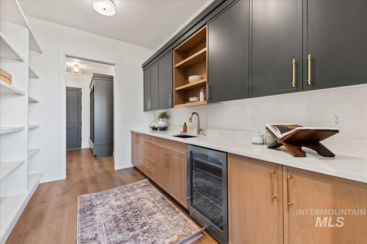 Bar with open shelves, beverage cooler, light quartz countertops, and light wood-style flooring