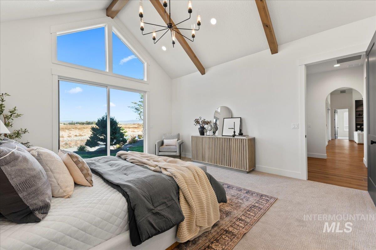Carpeted bedroom featuring high vaulted ceiling, arched walkways, beam ceiling, access to outside, and a chandelier