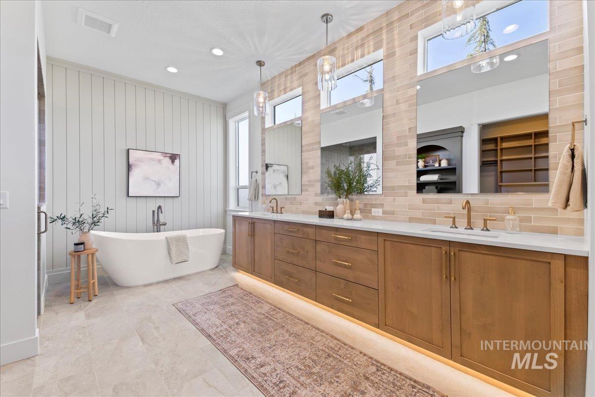 Bathroom with double vanity, a freestanding tub, a spacious closet, recessed lighting, and backsplash