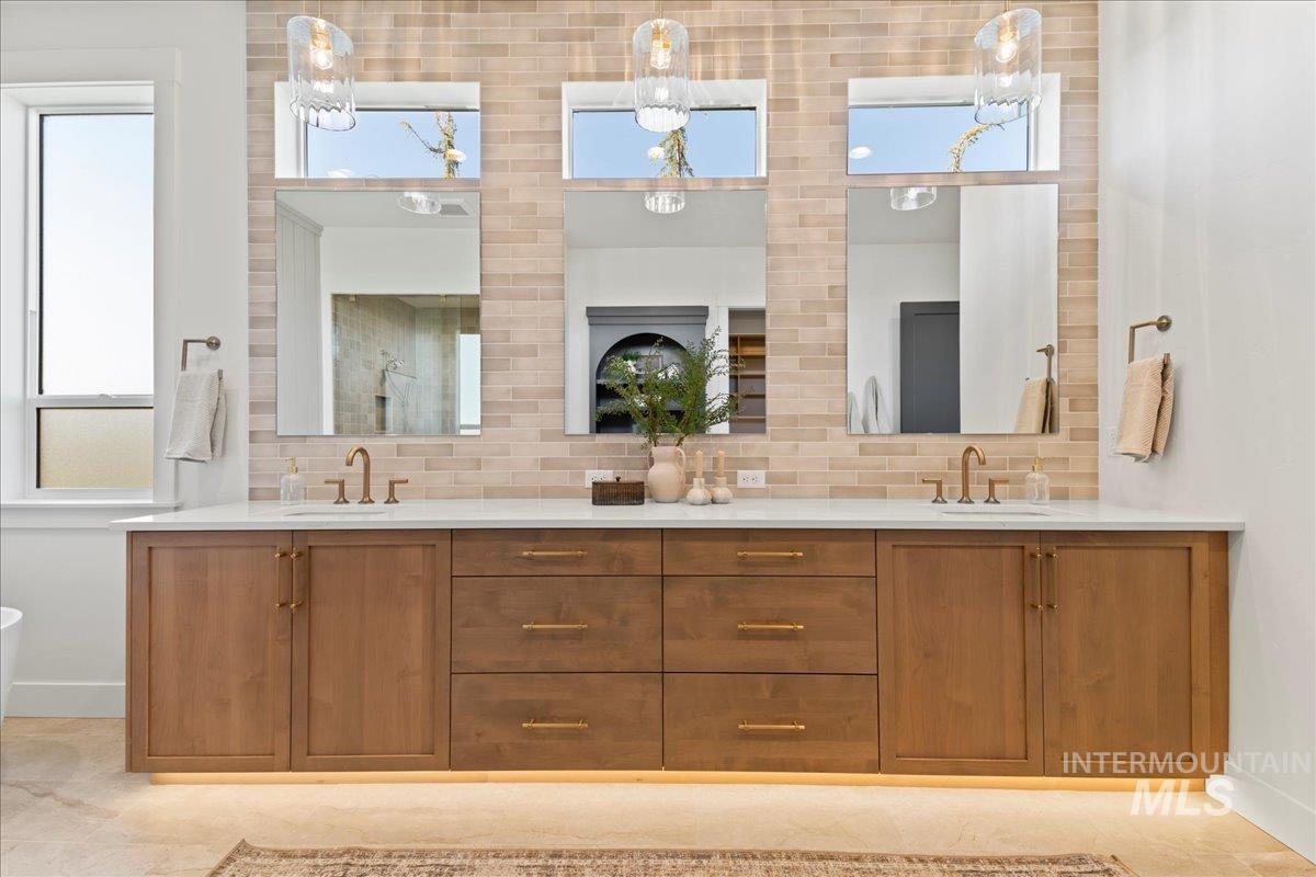 Bathroom featuring tasteful backsplash, double vanity, and light tile patterned floors