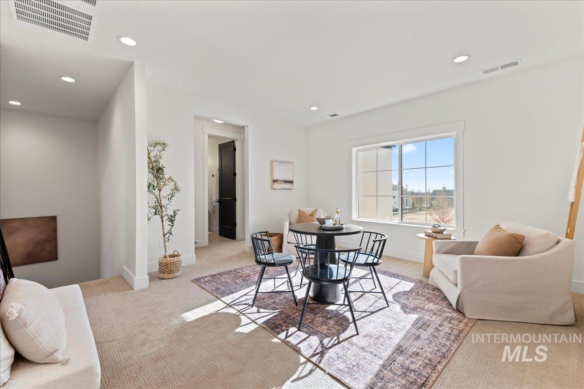 Loft space with light carpet and recessed lighting