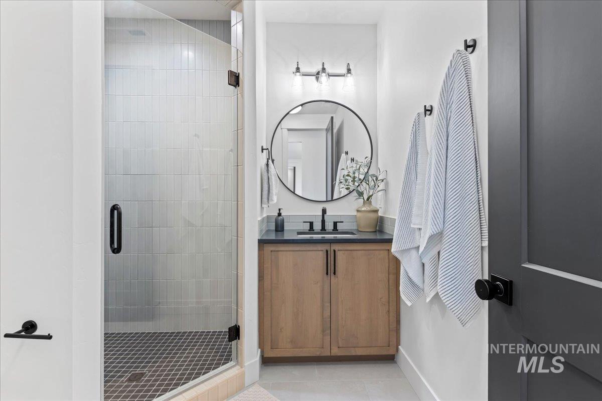 Full bathroom featuring light tile patterned floors, a shower stall, and vanity