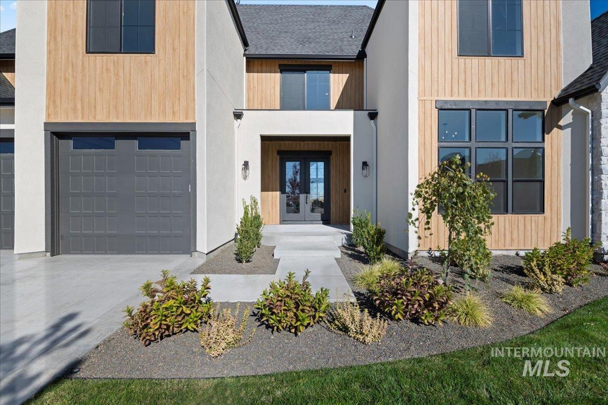 View of front of property featuring french doors, roof with shingles, concrete driveway, and an attached garage