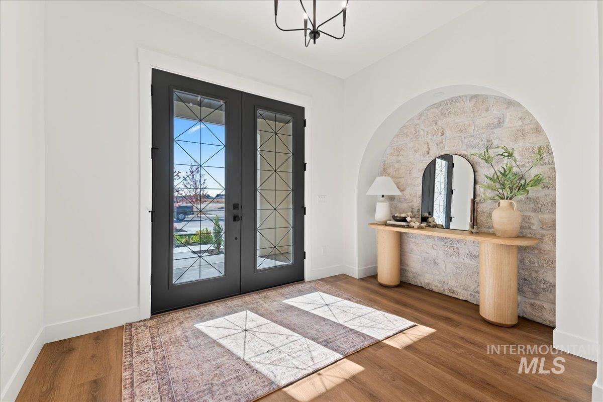Foyer with french doors, arched walkways, and wood finished floors