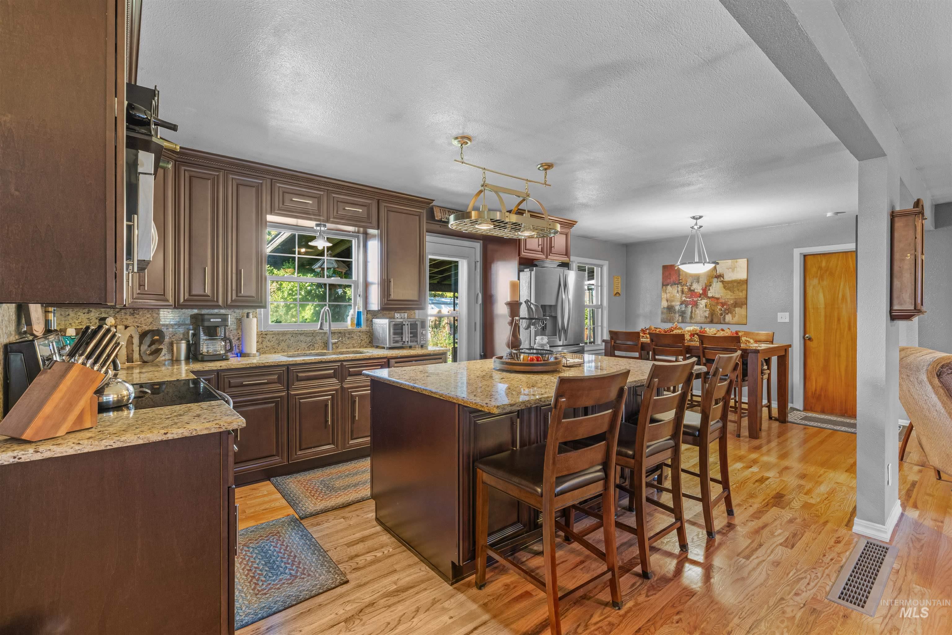 Kitchen with a kitchen breakfast bar, a center island, decorative light fixtures, granite counters, and a textured ceiling