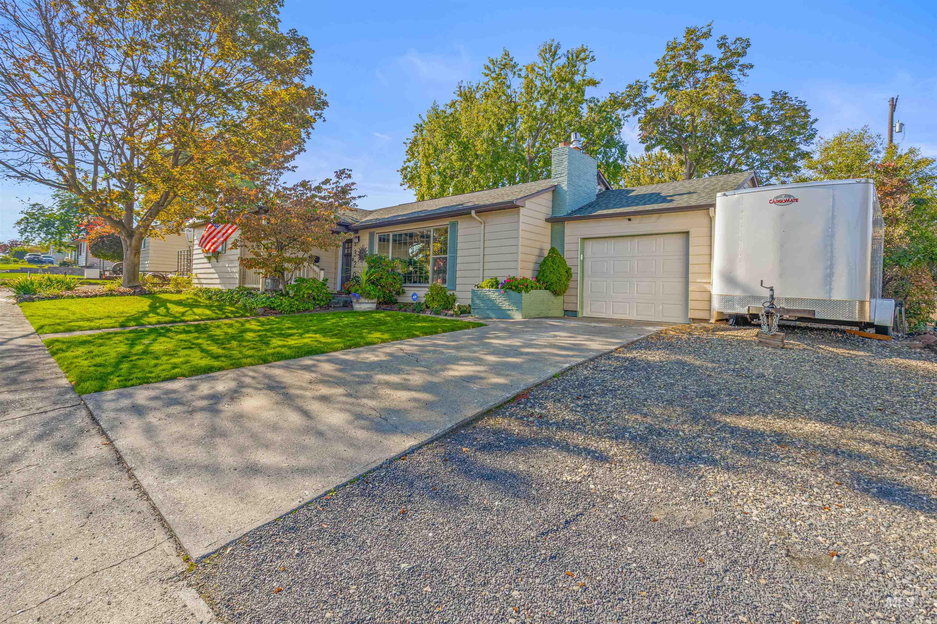 View of front of home with driveway, a garage and a front lawn