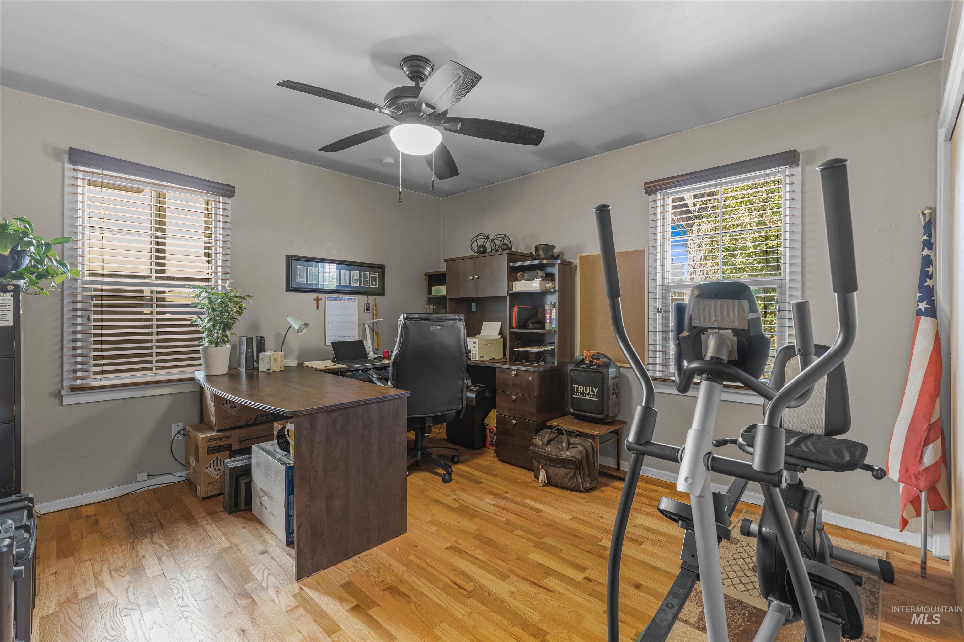 Main Floor bedroom being used as a office featuring light wood-style flooring and a ceiling fan