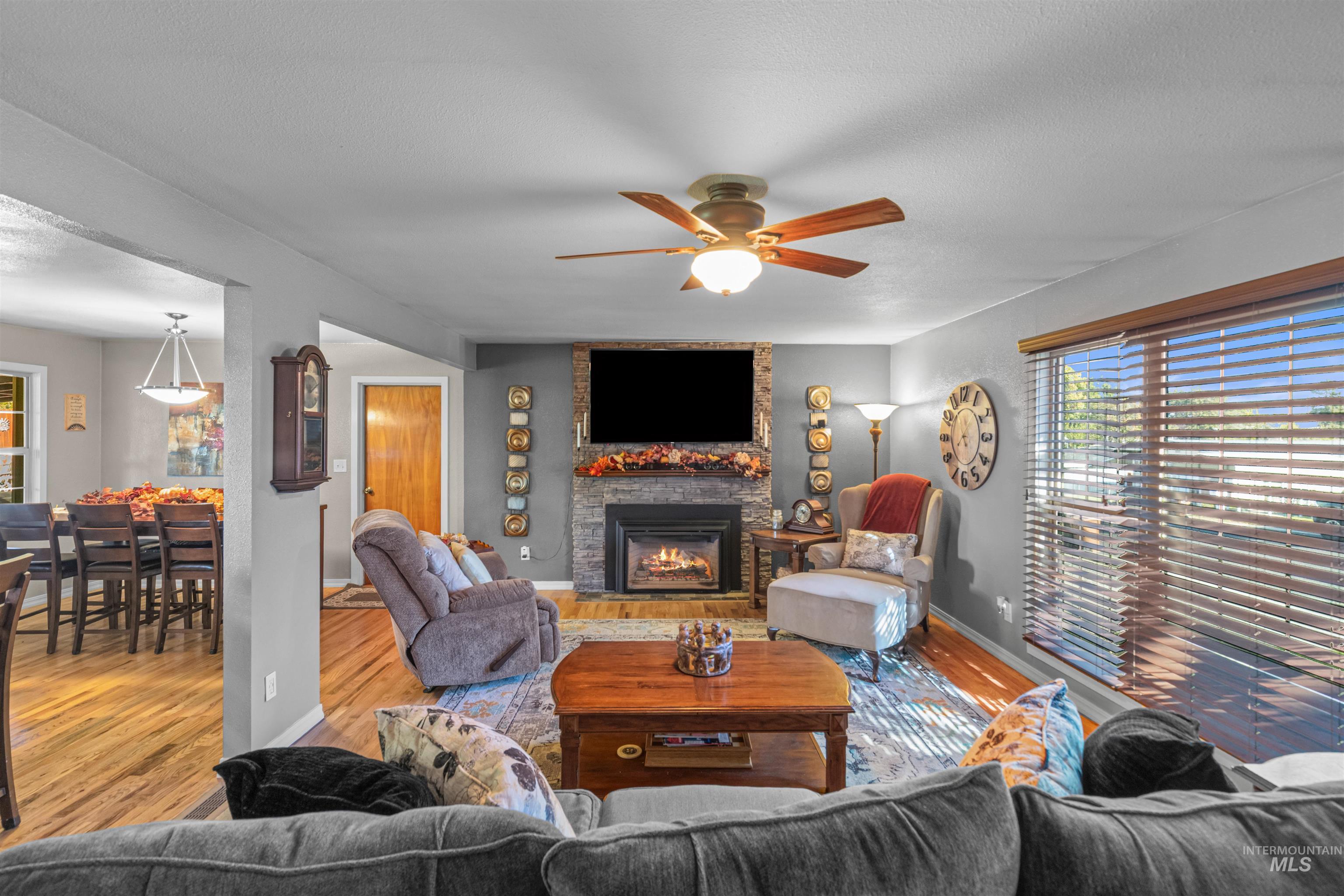 Living area with wood finished floors, a ceiling fan, a fireplace, and a textured ceiling