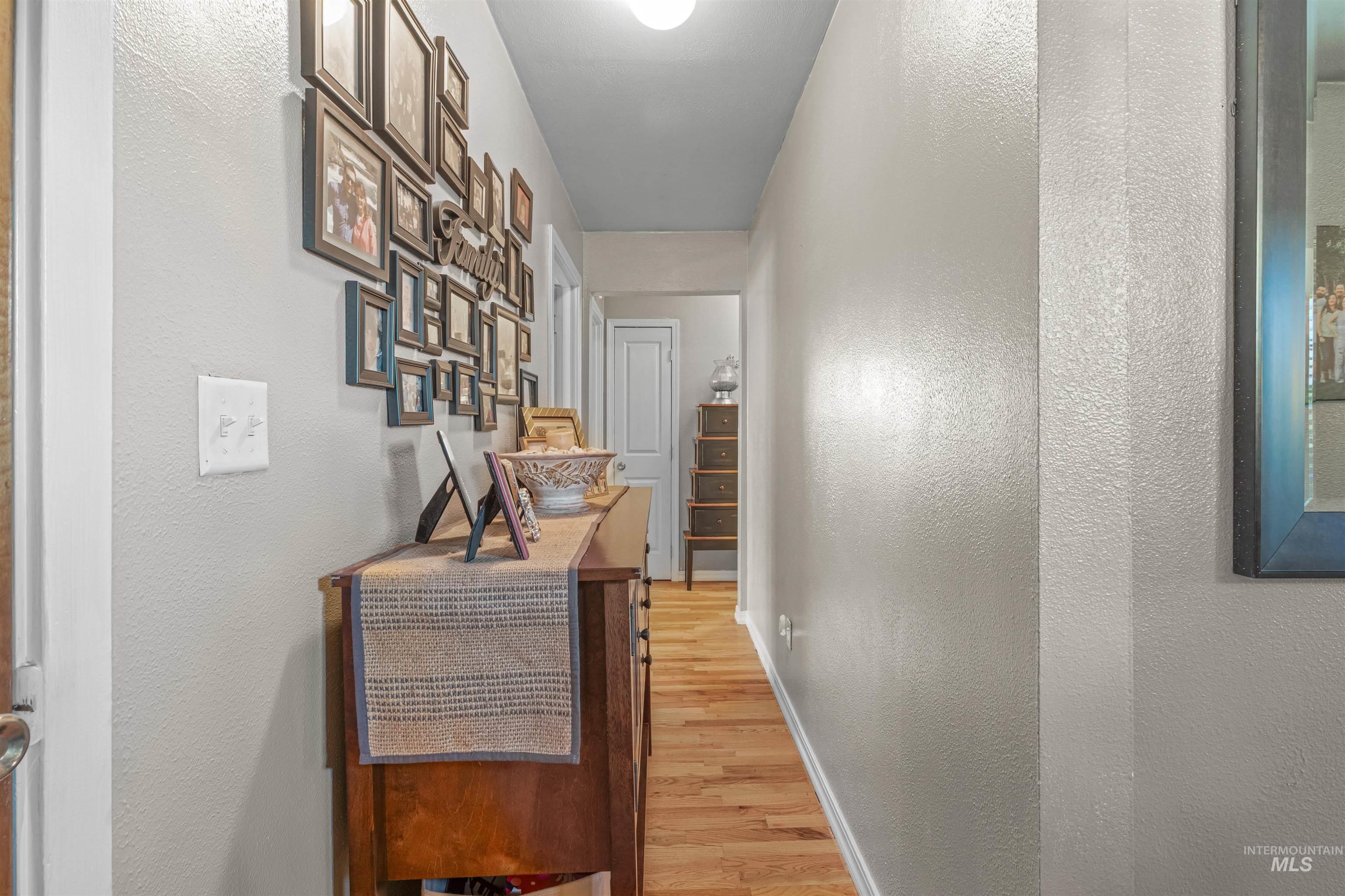Corridor with light wood-style flooring and a textured wall
