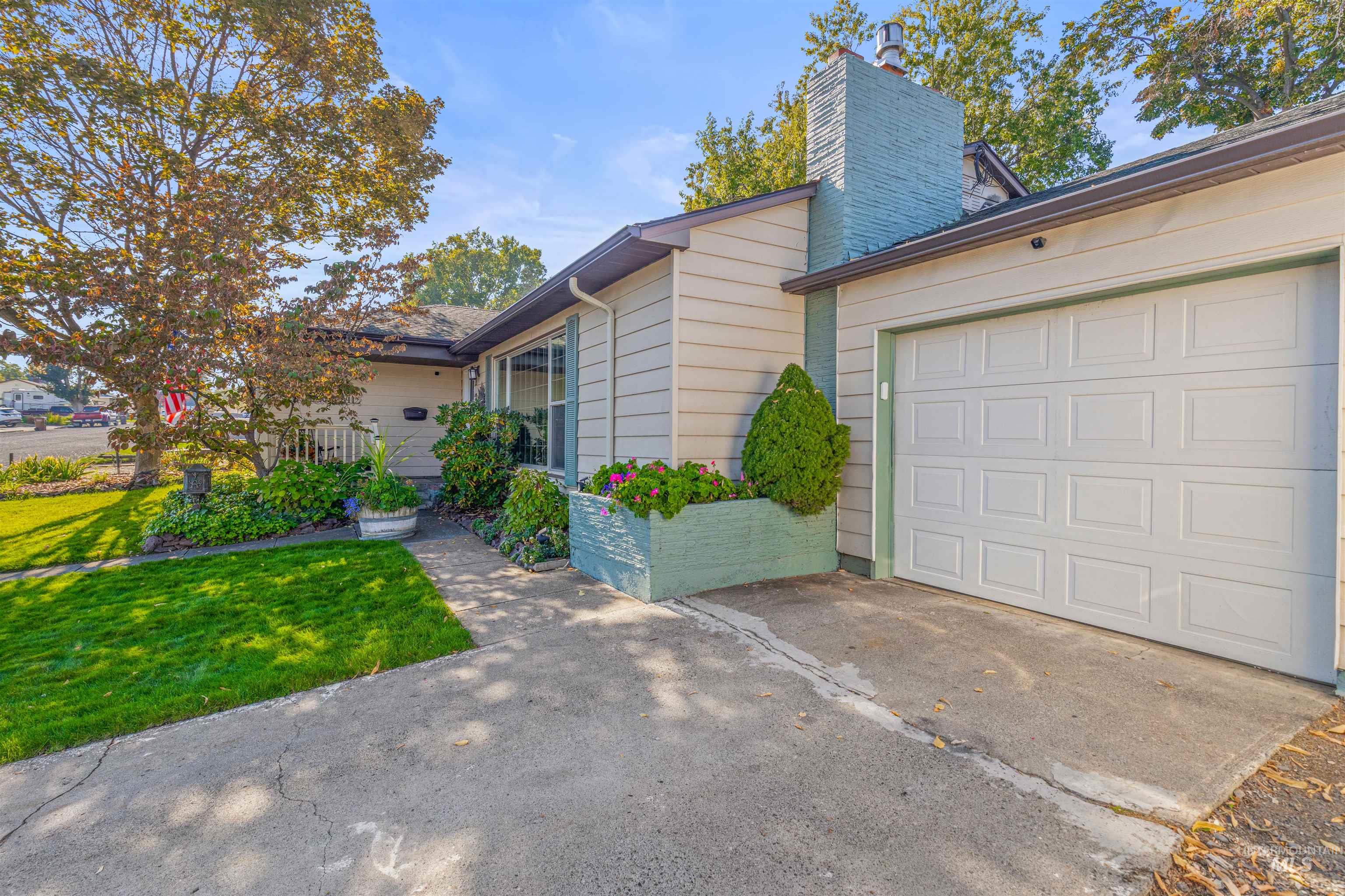 View of front facade featuring a front yard, a chimney, concrete driveway, and a garage