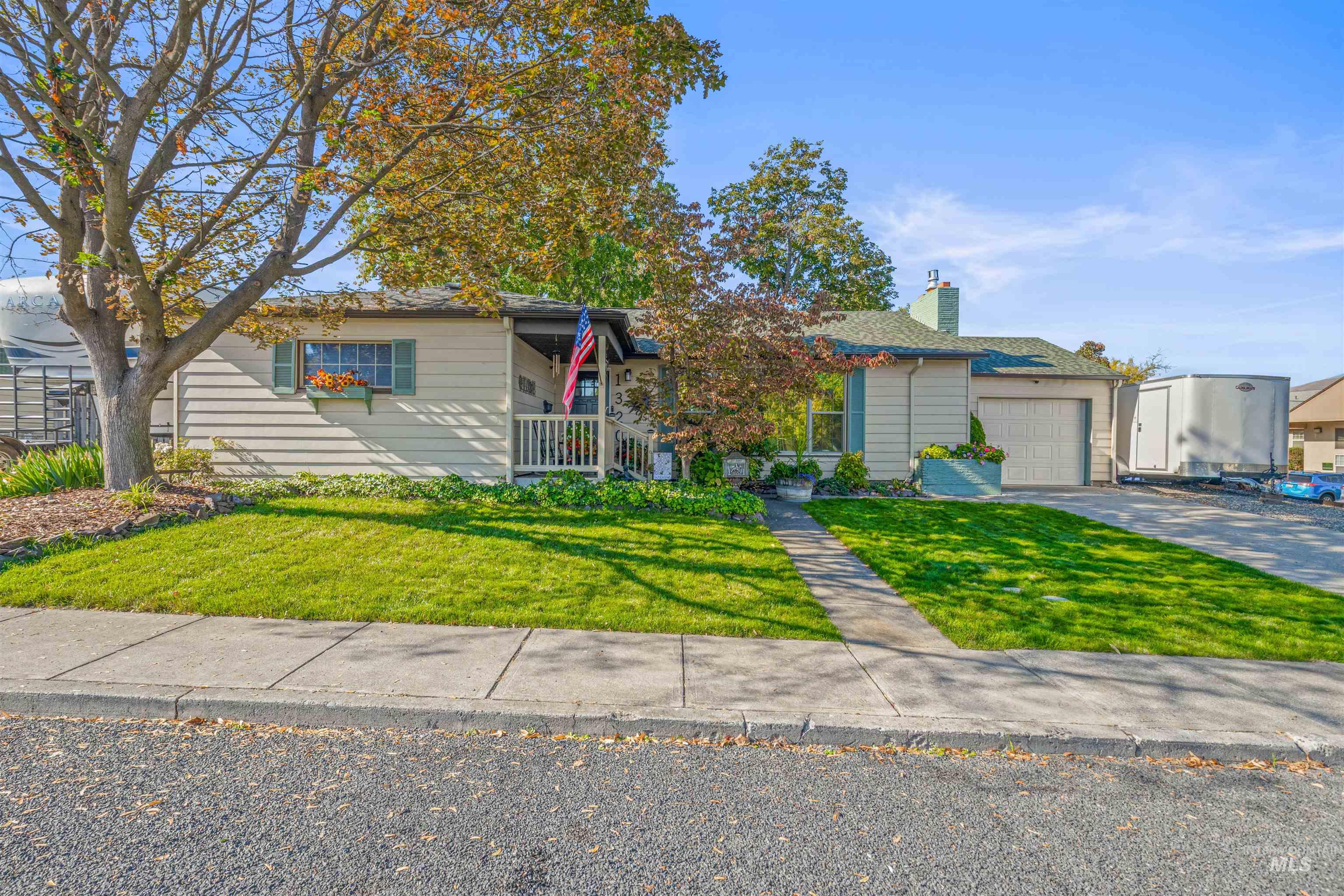 Ranch-style house featuring a front yard, a chimney, driveway, and an attached garage
