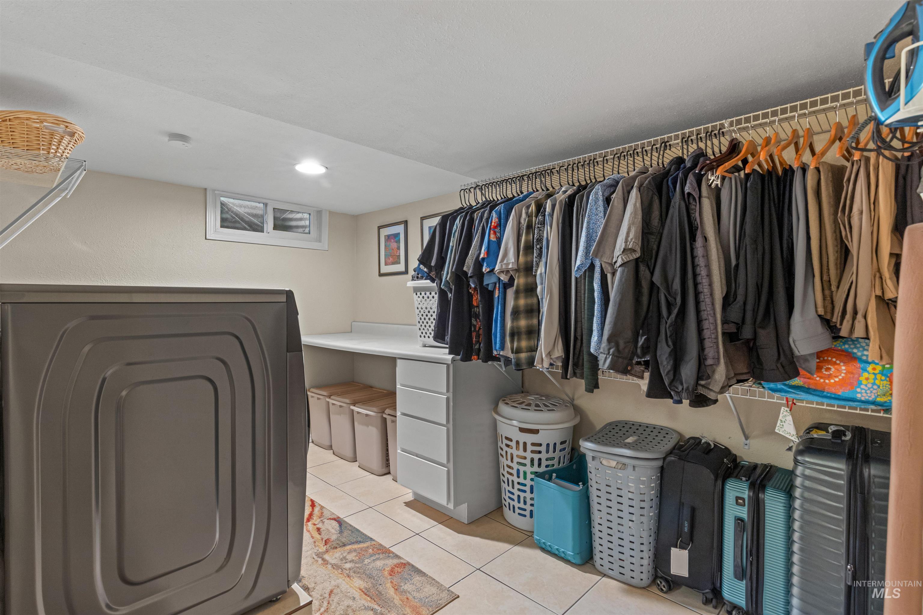 Spacious closet with washer / clothes dryer and light tile patterned flooring