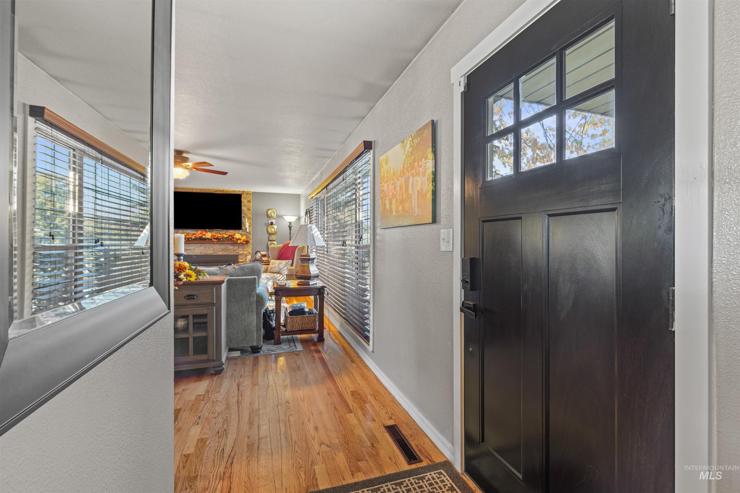Foyer featuring a textured wall, light wood-style floors, ceiling fan, and a fireplace