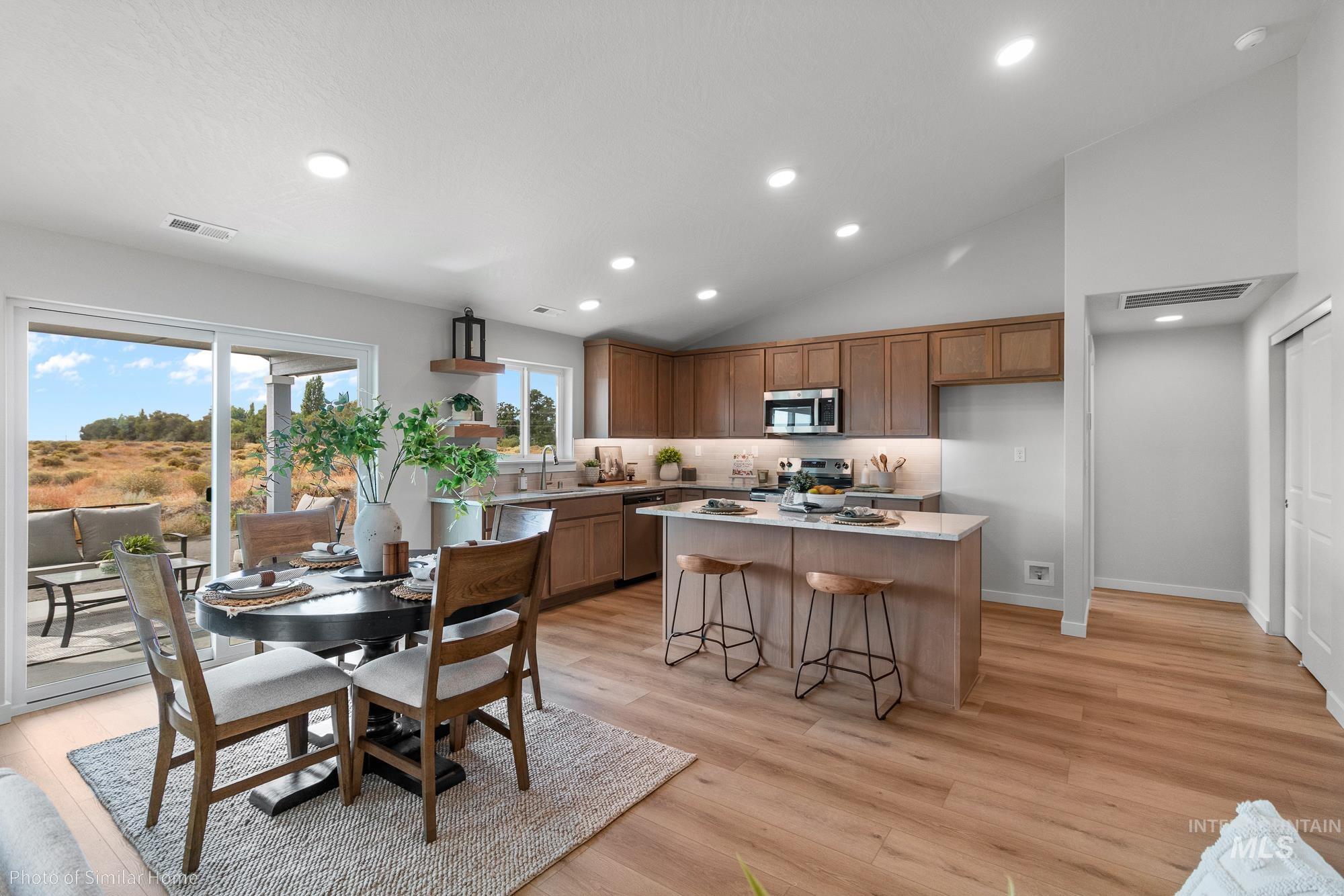 Kitchen with brown cabinetry, recessed lighting, light wood-type flooring, lofted ceiling, and a center island