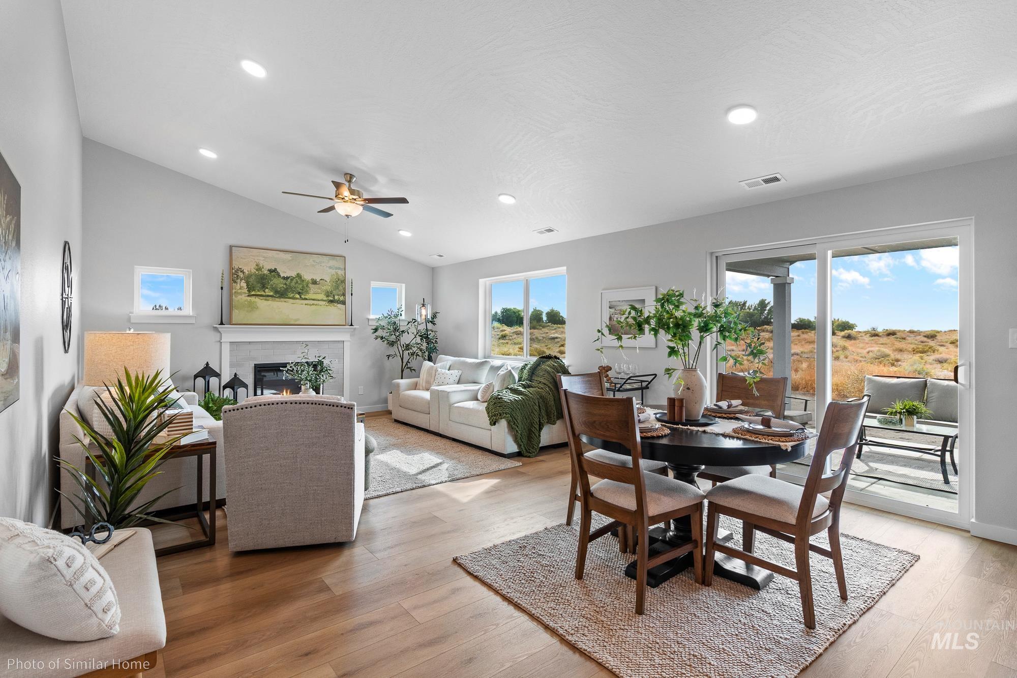 Dining area with healthy amount of natural light, light wood-type flooring, a glass covered fireplace, lofted ceiling, and recessed lighting