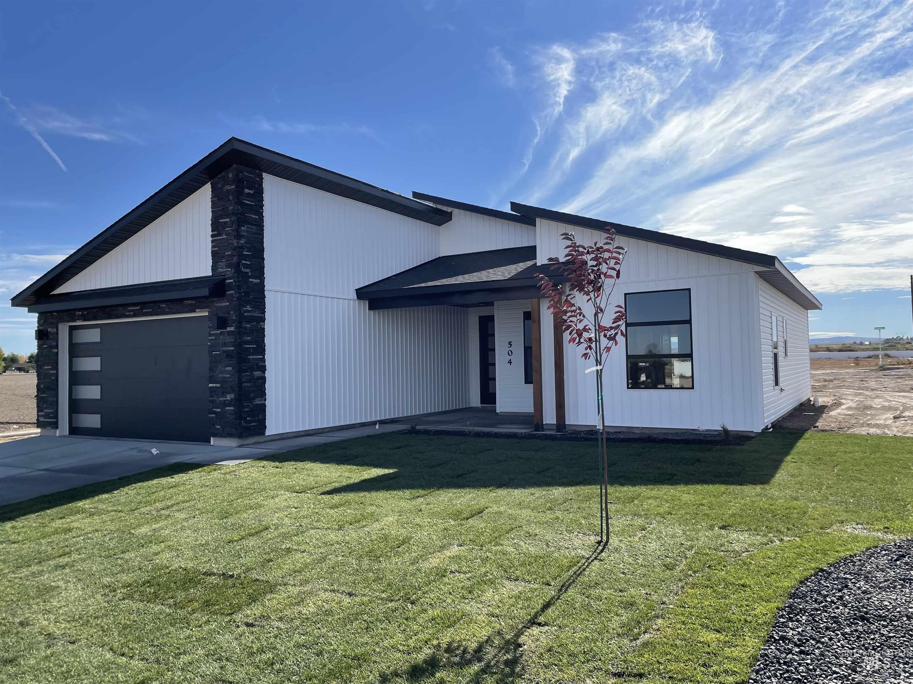 View of front facade featuring a garage, a front lawn, and driveway