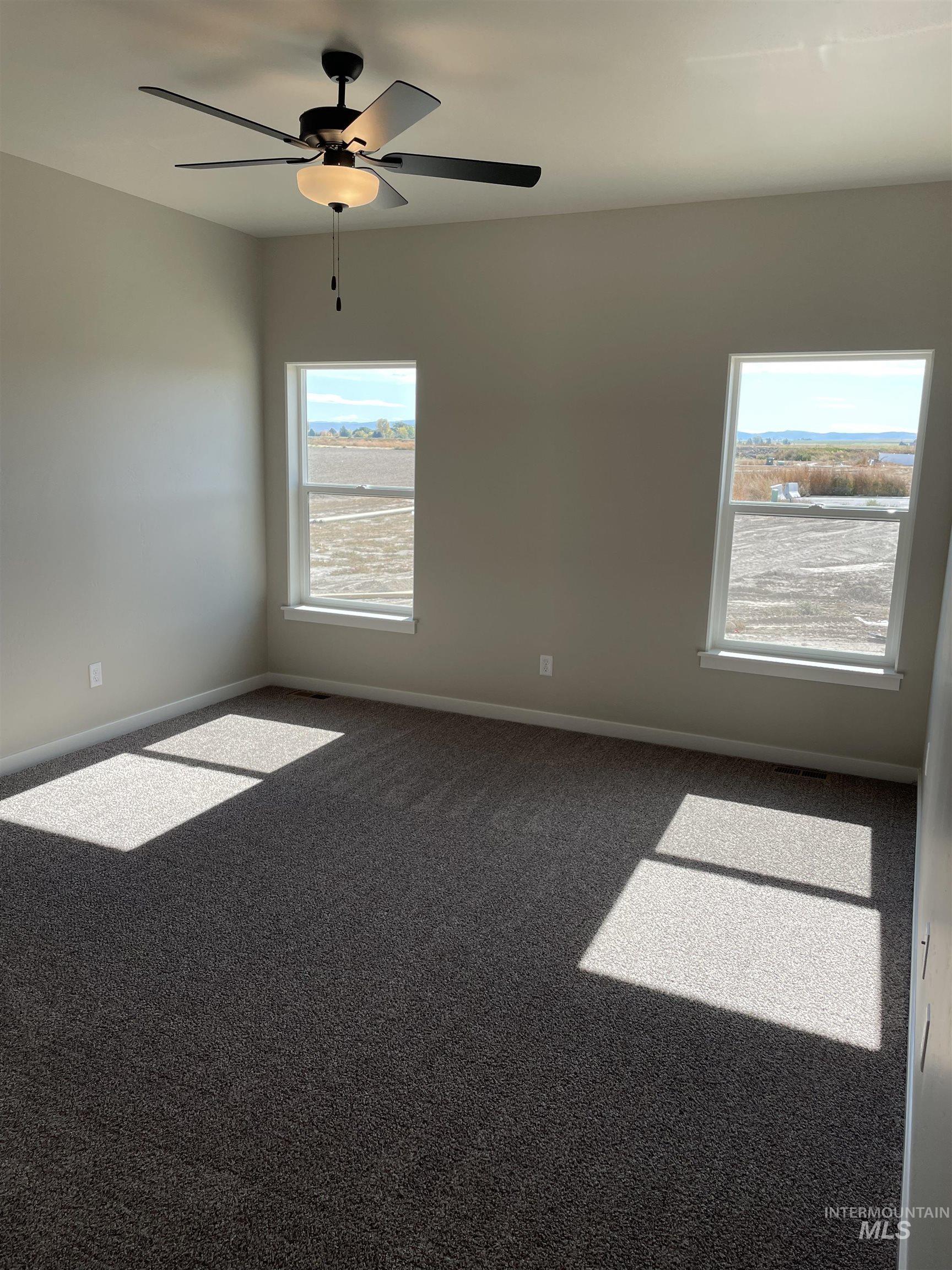 Carpeted empty room featuring baseboards and ceiling fan