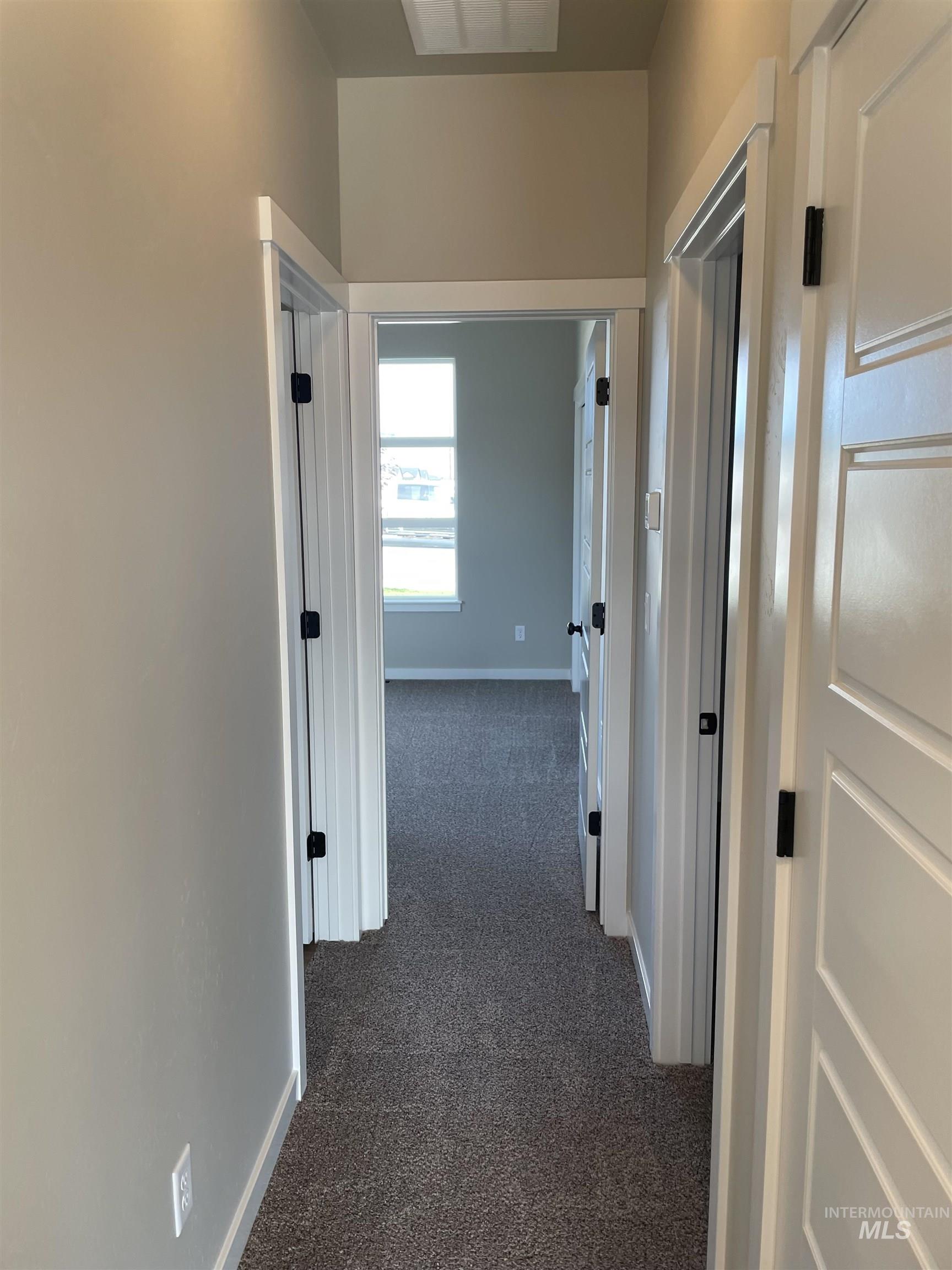 Corridor featuring dark colored carpet and baseboards