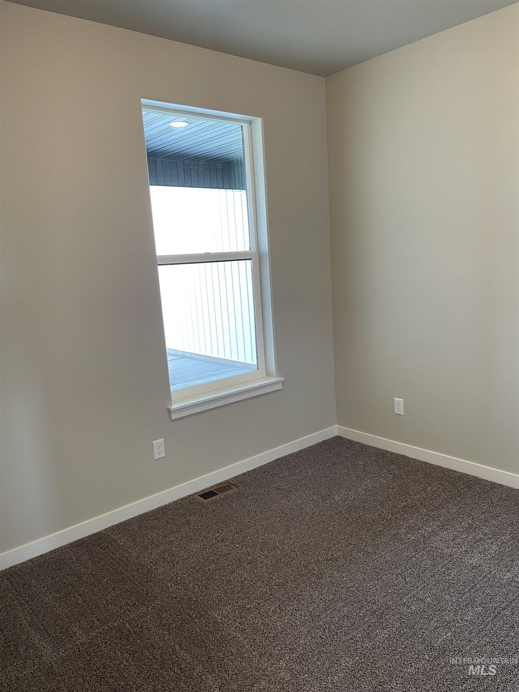 Spare room featuring dark carpet and baseboards
