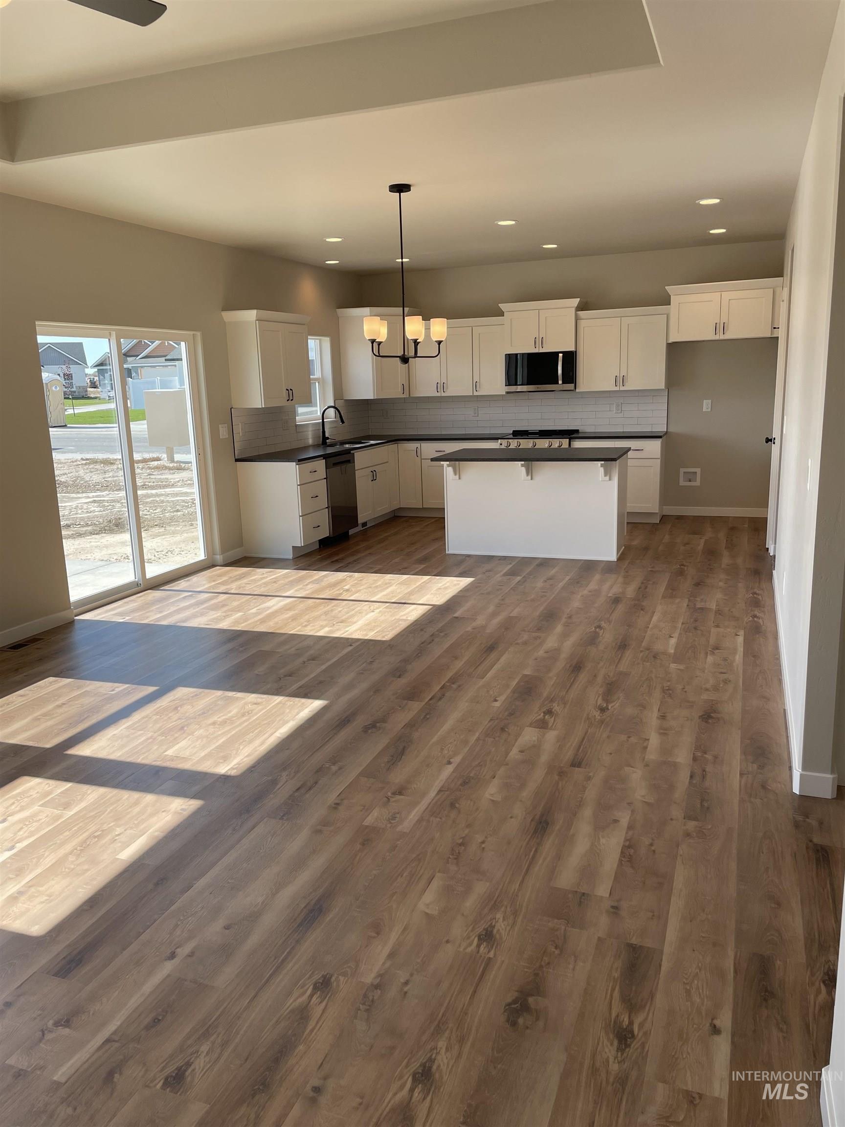 Kitchen with backsplash, dark countertops, white cabinets, a kitchen breakfast bar, and recessed lighting