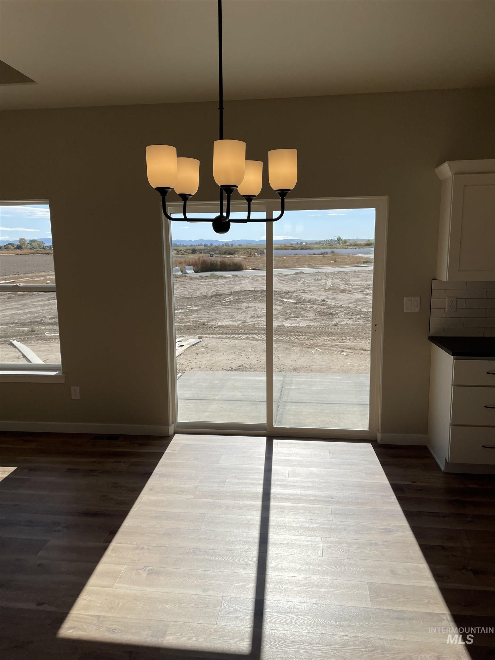 Unfurnished dining area with dark wood-style flooring and a chandelier