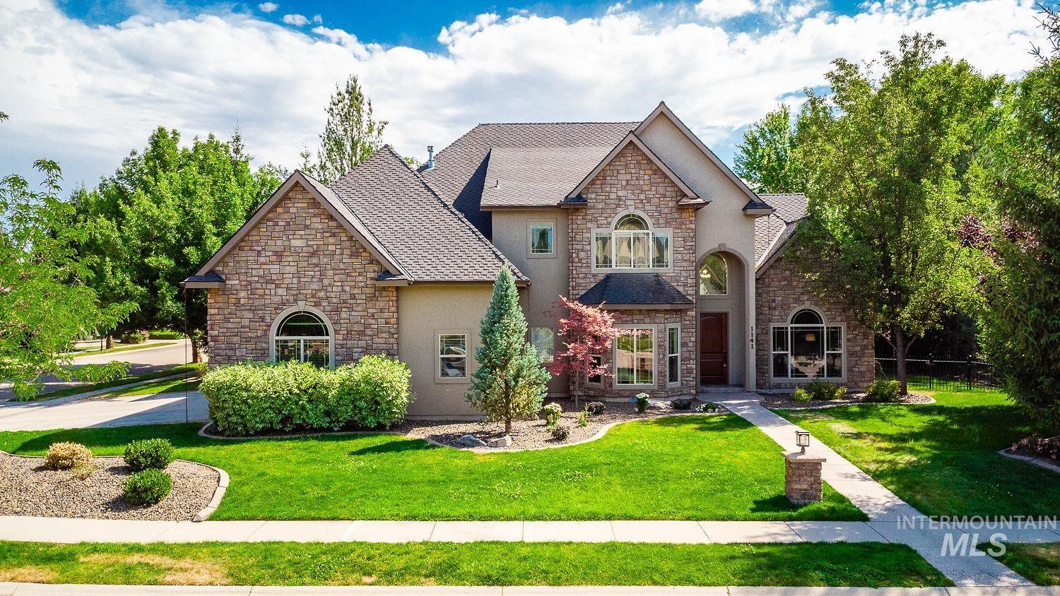 French provincial home with stone siding, a front yard, stucco siding, and a shingled roof