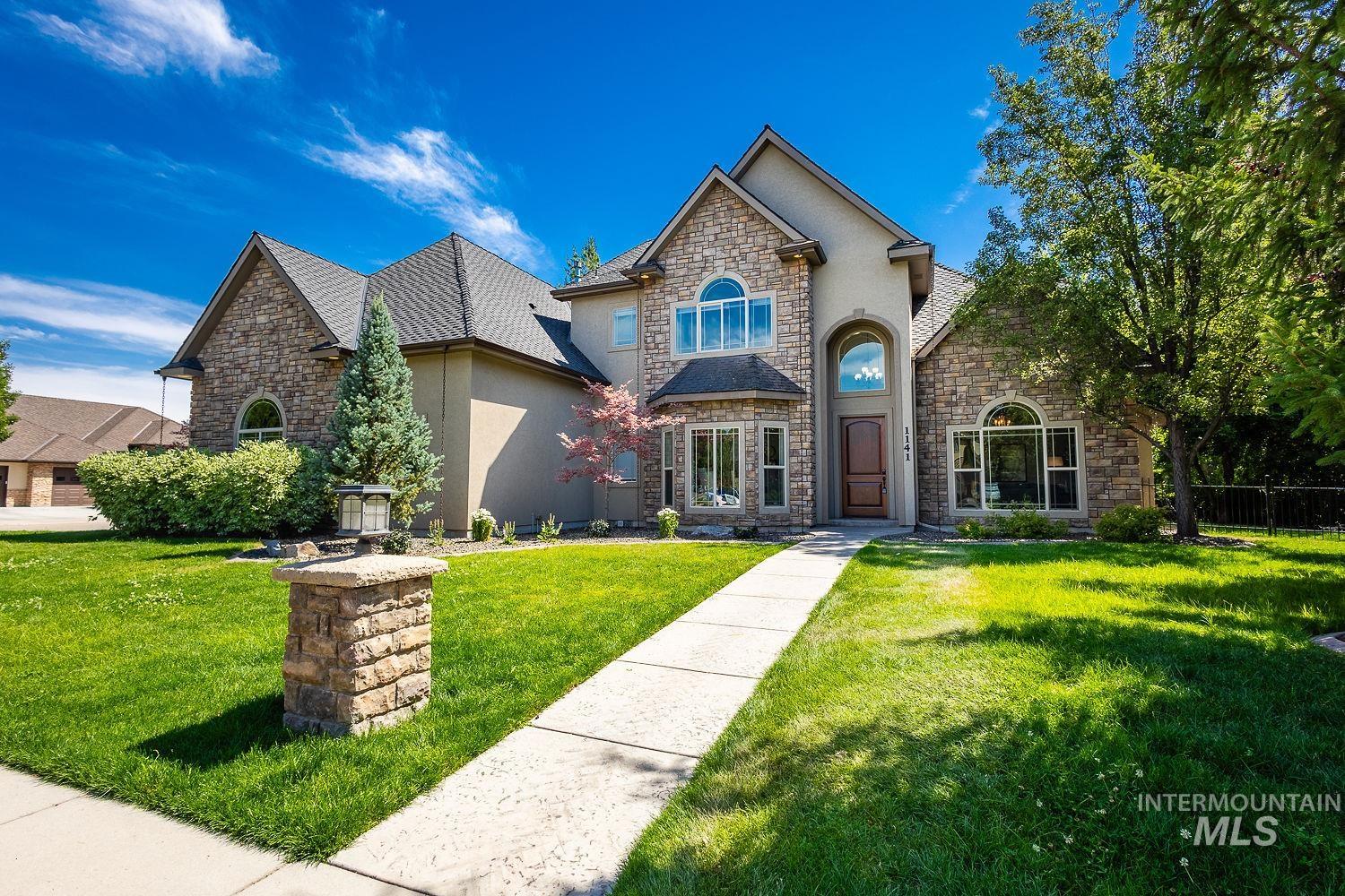 French country style house with stone siding, a front lawn, and stucco siding