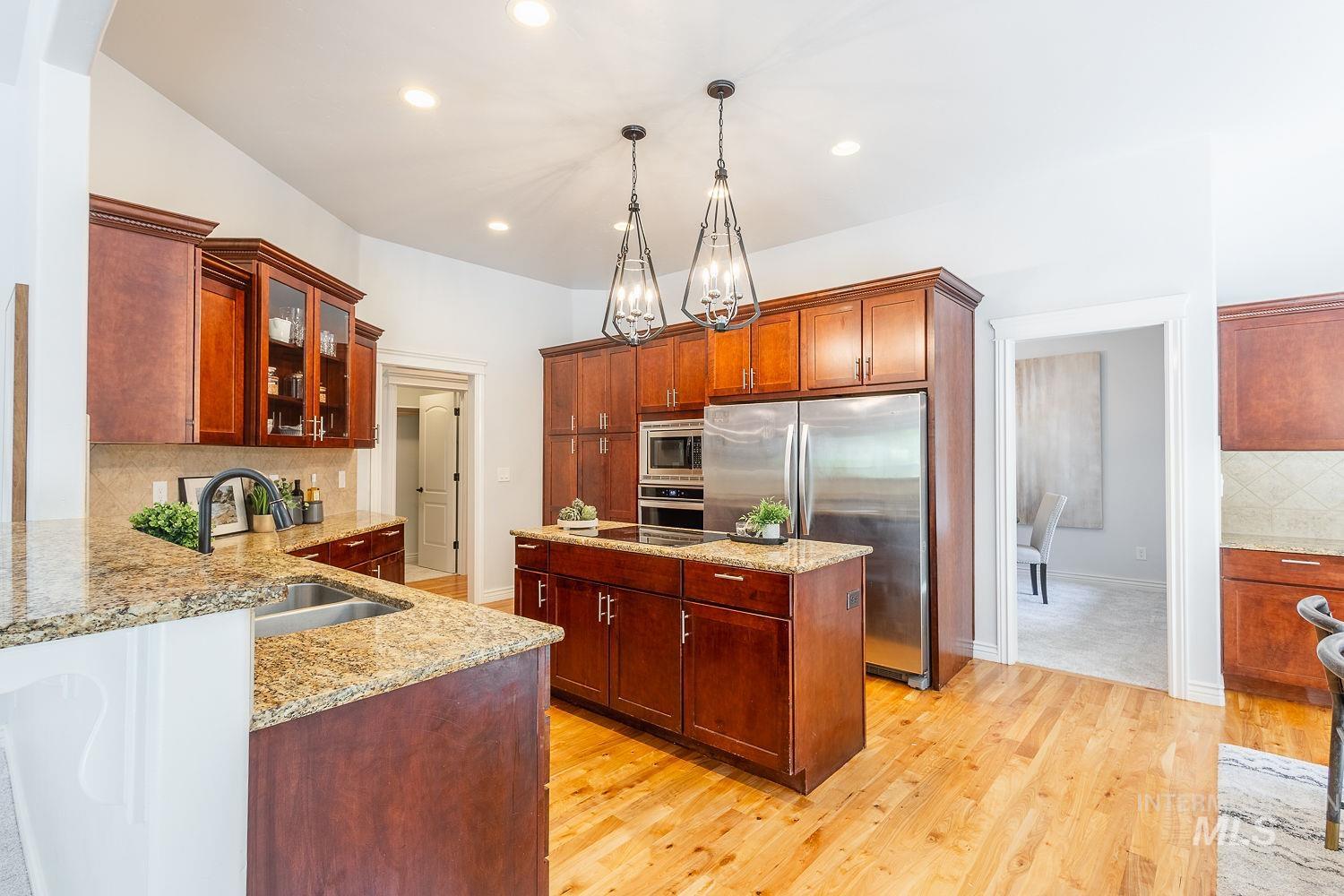Kitchen featuring decorative backsplash, a center island, glass insert cabinets, appliances with stainless steel finishes, and decorative light fixtures