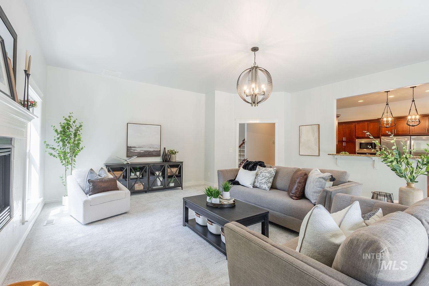 Living area with light colored carpet, a glass covered fireplace, a chandelier, and recessed lighting