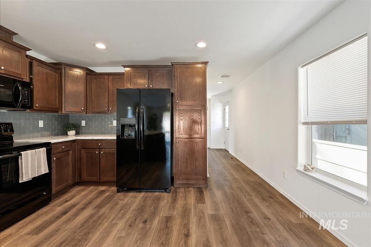 Kitchen with black appliances, decorative backsplash, dark brown cabinetry, dark wood-style floors, and recessed lighting
