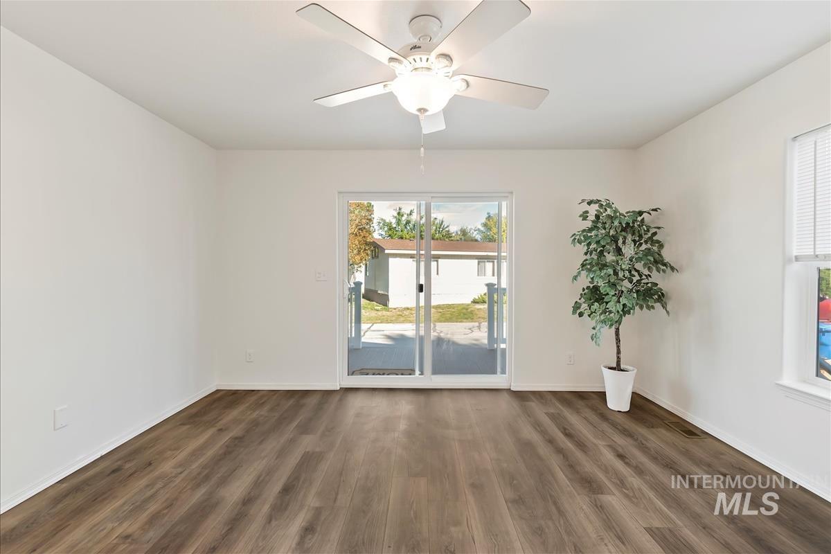 Empty room with dark wood-type flooring and a ceiling fan