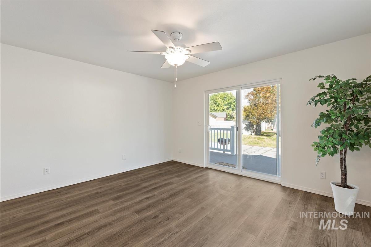 Empty room featuring dark wood-type flooring and a ceiling fan