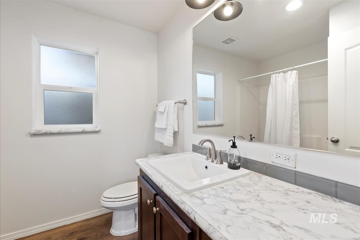 Full bathroom featuring dark wood-style floors, curtained shower, vanity, and recessed lighting