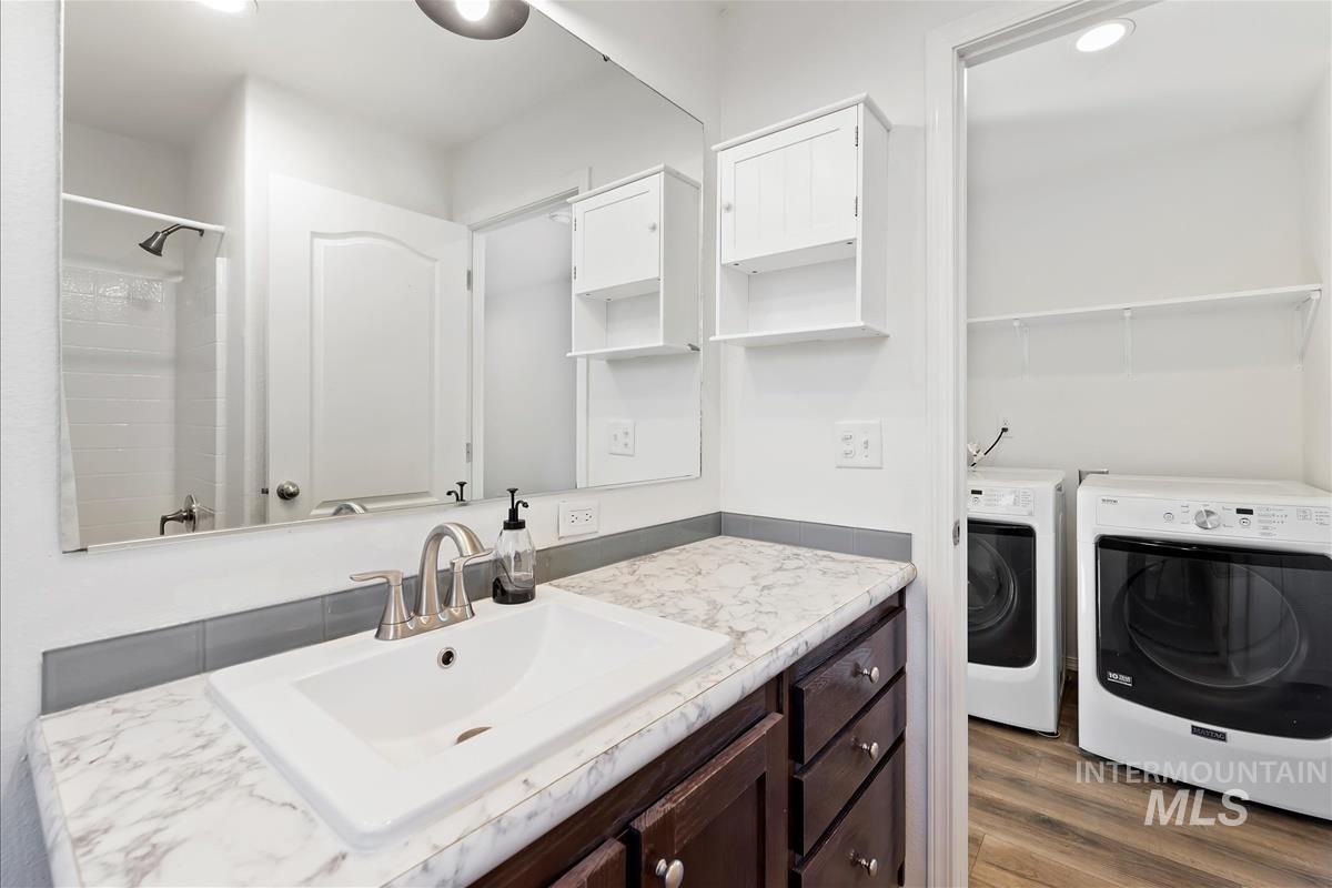 Full bathroom featuring vanity, dark wood-type flooring, recessed lighting, independent washer and dryer, and a shower