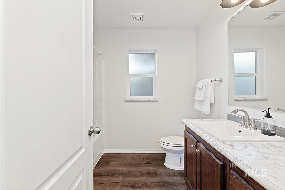 Full bathroom with vanity and dark wood-style flooring