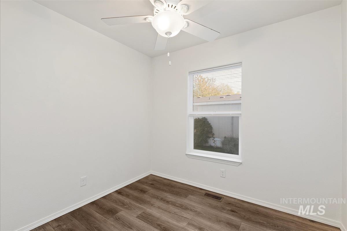 Spare room featuring dark wood-style flooring and a ceiling fan