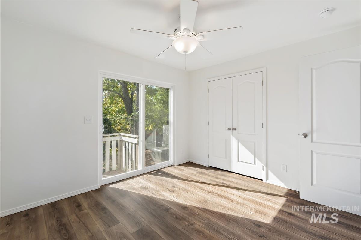 Unfurnished bedroom featuring wood finished floors, a closet, access to outside, and a ceiling fan