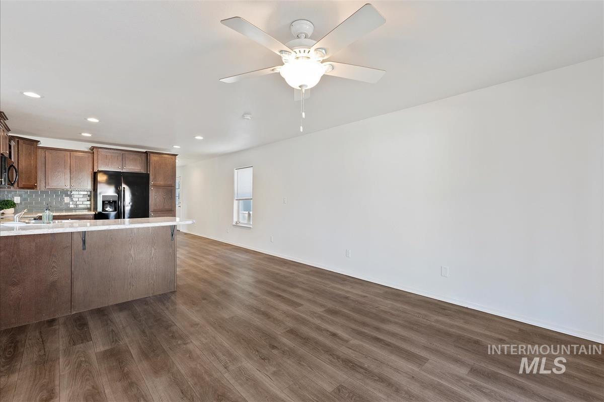 Kitchen featuring light countertops, black fridge with ice dispenser, recessed lighting, tasteful backsplash, and a peninsula