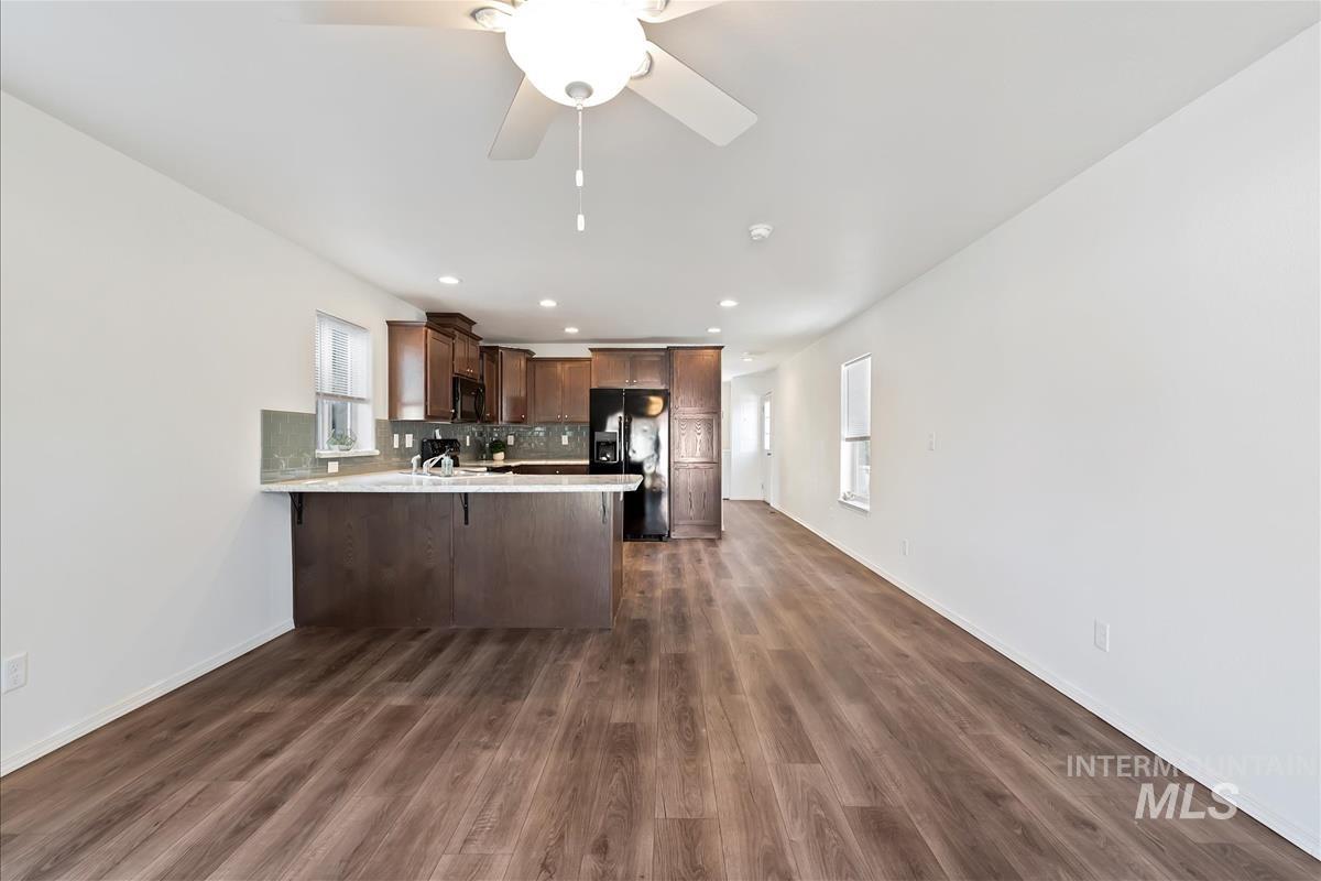 Kitchen with plenty of natural light, a peninsula, black appliances, tasteful backsplash, and recessed lighting