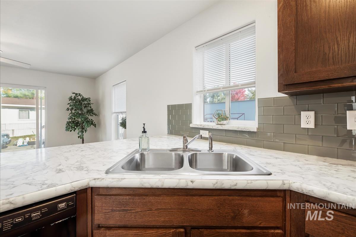 Kitchen with light countertops, dishwasher, plenty of natural light, and backsplash